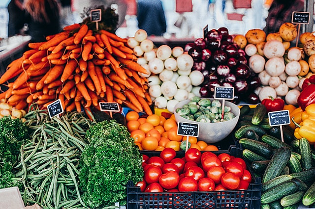 Sur une étale de marché, on voit des fruits et légumes colorés et des ardoises annoncent le prix. / applis éco-responsable
