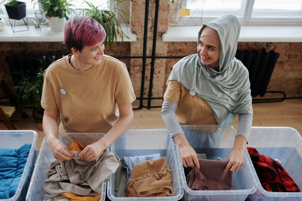 Deux femmes rangent des vêtements dans des boites pour une association / conseils pour ranger son dressing