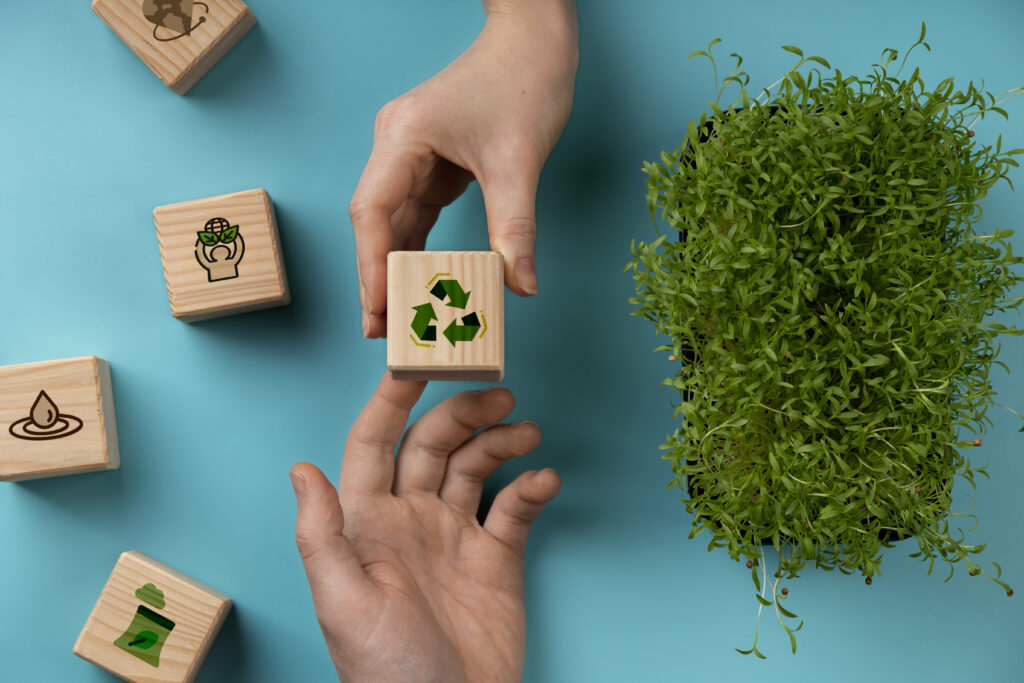 deux mains se passant un cube en bois avec un symbole recyclage