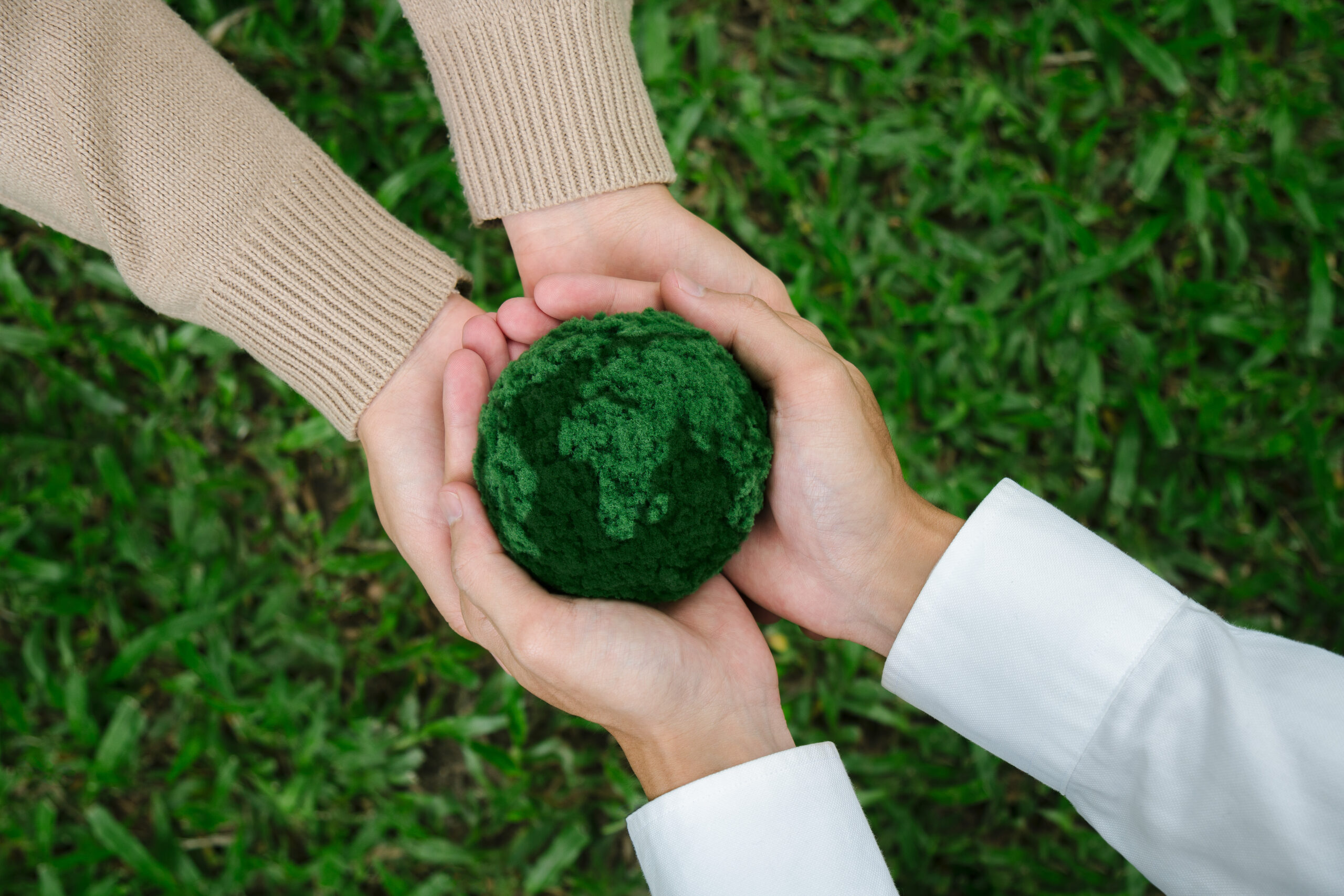 Two hands holding green earth together on nature background for