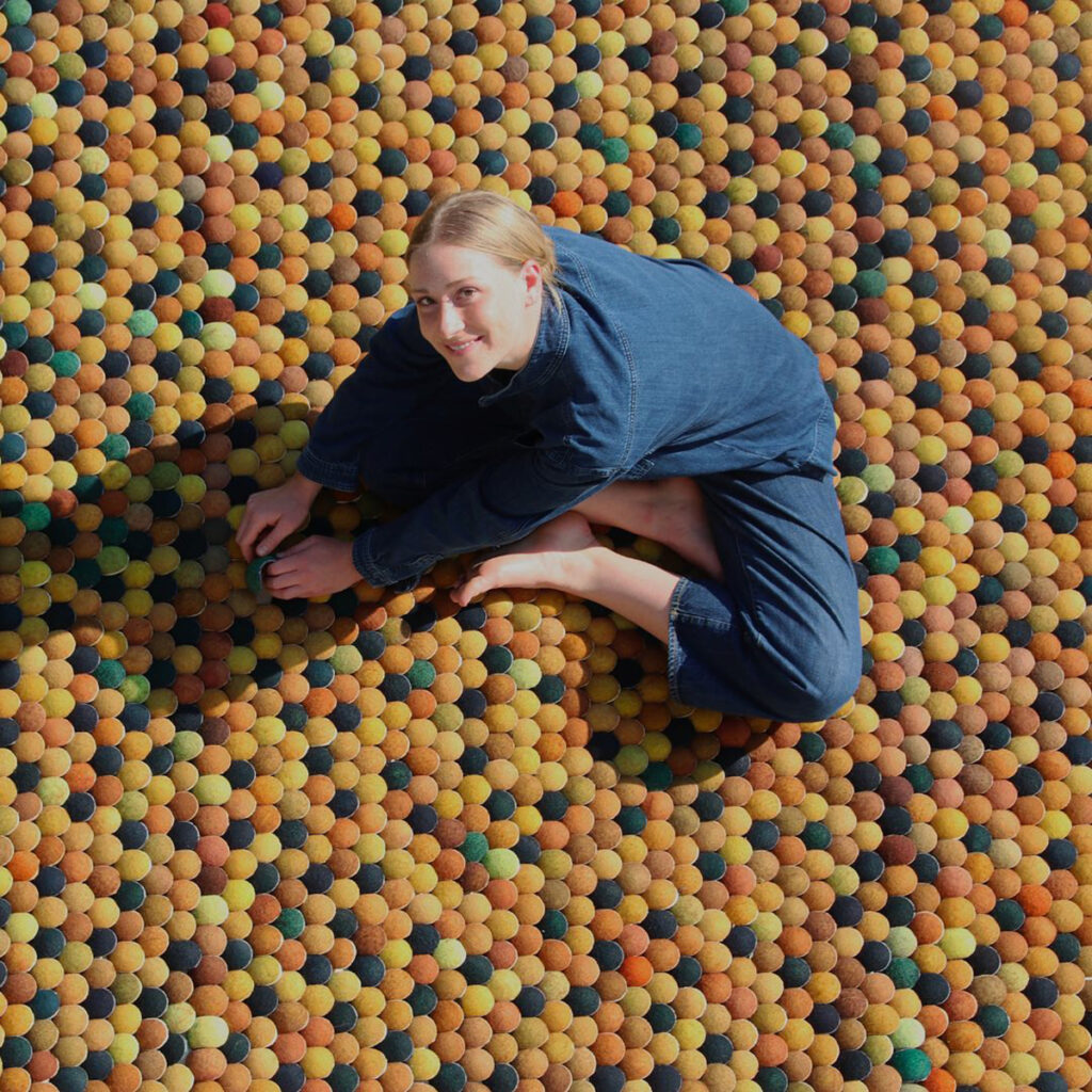 Mathilde Wittock qui pose sur un fond de balles de tennis colorées et réutilisées pour une de ses créations.